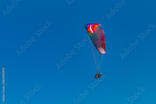 Paraglider flying in the blue sky