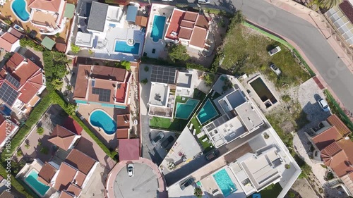Spinning drone shot over suburban houses with pools, solar panels, and modern architecture