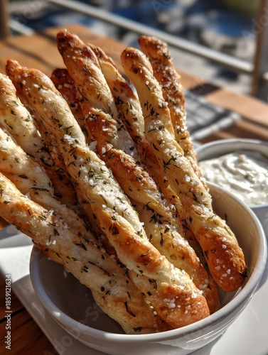 Golden sourdough discard breadsticks with herbs and sea salt in white bowl
