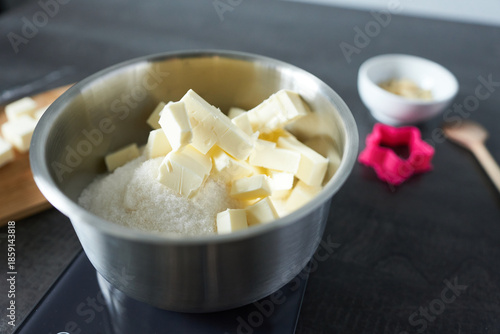 Chopped butter in a stainless steel bowl on a black countertop. Homemade baking in progress.