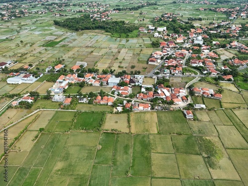 Wide aerial view of suburban town with red roof houses blending into green farmland landscape