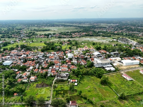 Wide aerial view of suburban town with red roof houses blending into green farmland landscape