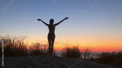 Silhouette of woman in bikini on sandy dune at sunset mood warm calm peaceful beach scene inspiring relaxation freedom.