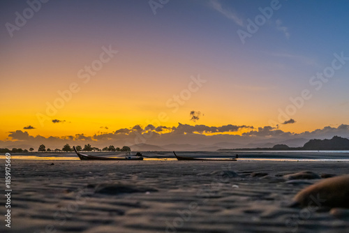 Traditional Longtail Boats at Low Tide Under Golden Sunset Sky