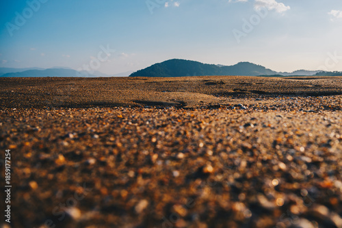 Low-Angle Sandy Beach with Distant Hills Under Clear Blue Sky