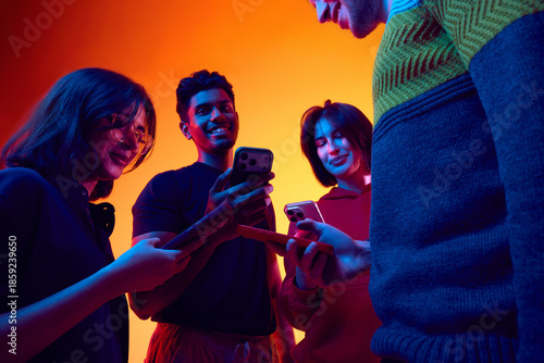 Fotografía Friends checking smartphones in colorful studio lighting
