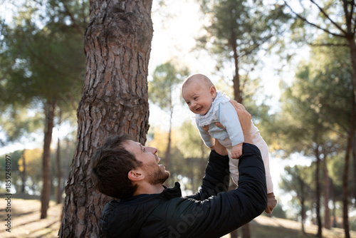 Happy father lifting baby in air playing outdoors