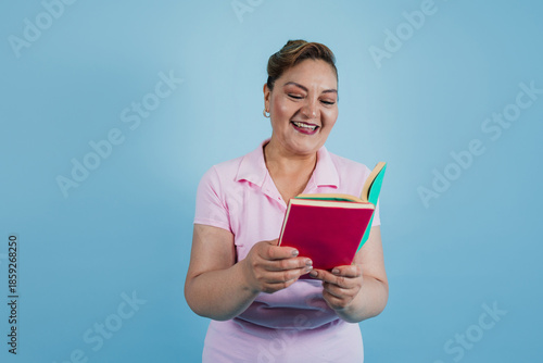 adult hispanic woman reading a book isolated over blue background in Mexico Latin America