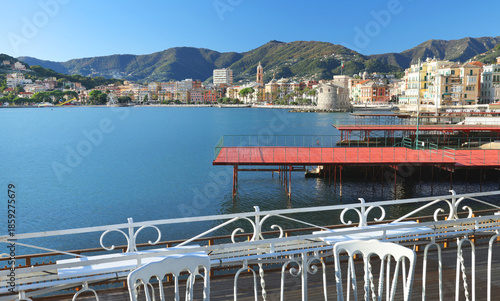Panoramic view of traditional buildings and structures of Liguria. Mountains of Italy. Mediterranean nature, Europe. Sky, sea, and palm trees of Rapallo. Design backdrop. Tourism and recreation.