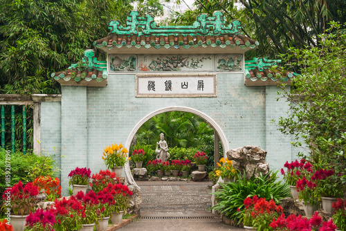 Photography The beautiful chinese circle entrance gate into Lou Lim Ieoc public garden with sculpture of young woman and crane surrounded by lush and bright flowers and green leaves