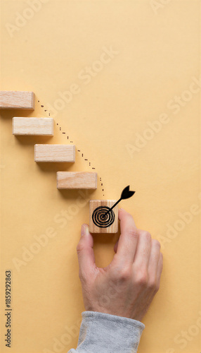 Hand arranging wooden steps toward target symbol