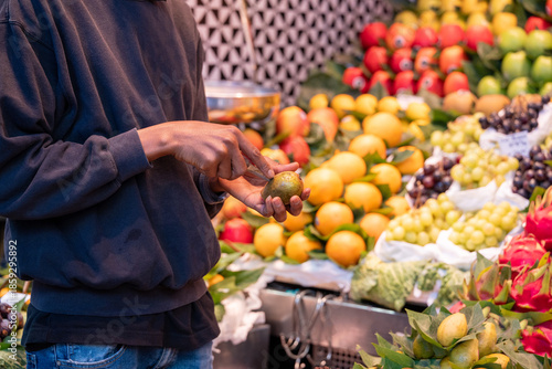 Person examining an avocado among fresh produce at a vibrant fruit stand