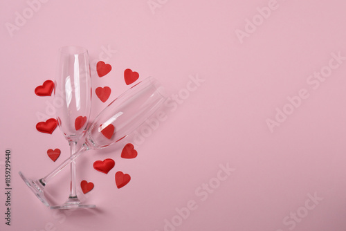 Festive background with a bottle of champagne, two glasses and hearts and gift boxes. A romantic date on Valentine's Day
