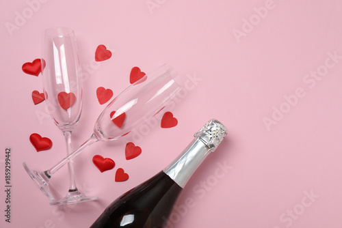 Festive background with a bottle of champagne, two glasses and hearts and gift boxes. A romantic date on Valentine's Day
