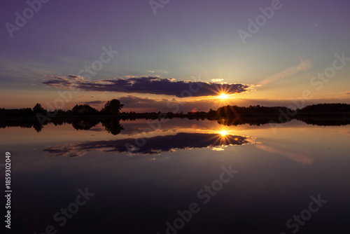Mirror reflection of clouds and sunset in the water of a calm lake
