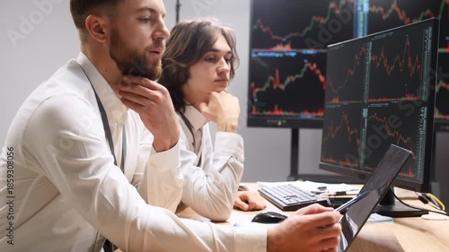 Focused at work, analyzing the data. Two male exchange workers are in the office together