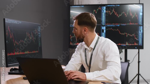 The document is in notepad. Handsome businessman is in the office with stock exchange market information on displays.