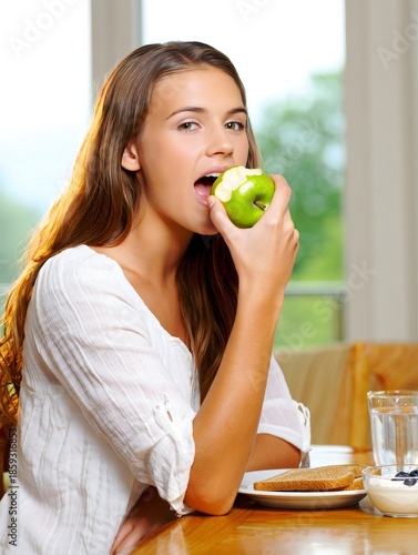 Healthy Young Woman Eating Green Apple at Breakfast