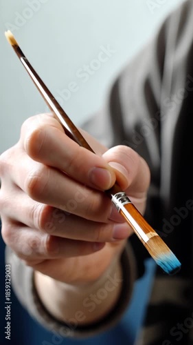 Artist uses brush to mix colors on a palette in a bright studio while preparing for a painting session in the afternoon