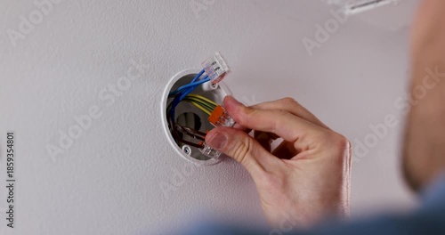Electrician connects wires with splicing connectors in drywall junction box. electrical services