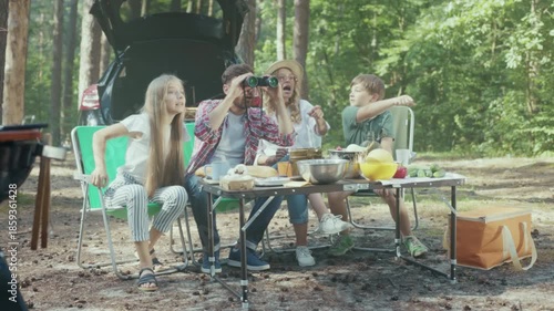 Family observes birds, Parents and children immerse in birdwatching adventure with gear in sunny woodland scene