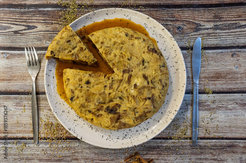 Spanish omelet with sauce on rustic wooden table