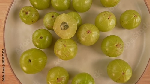 Indian gooseberry fruits on plate rotation top view. Selective focus. Amla. Phyllanthus emblica.