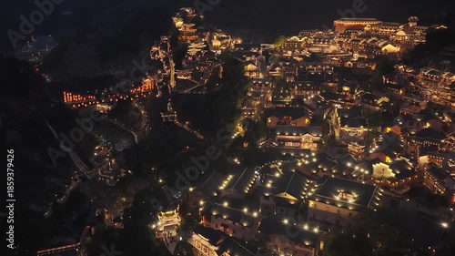 Aerial view of Wangxian Valley illuminated with a warm glow, nestled between dark hillsides, creating a striking contrast, Wangxian, China.