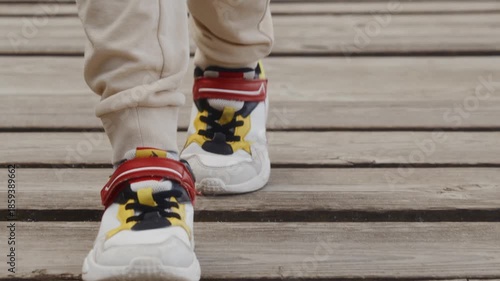 Close-up of sneakers walking on wooden pier. Represents small but confident steps of independence and personal growth. High quality 4k footage