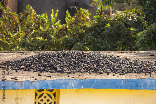 Pile of construction gravel on concrete roof in rural India
