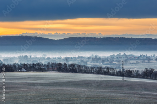 OLYMPUS DIGITAL CAMWinter morning in Zabierzów near Krakow. Frosted fields and misty valley with a plane taking off from Balice Airport against the breathtaking backdrop of the snowy Tatra MountainERA