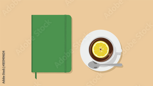 Top-down view of a cozy workspace with a closed green notebook and a cup of tea with a lemon slice on a neutral background.