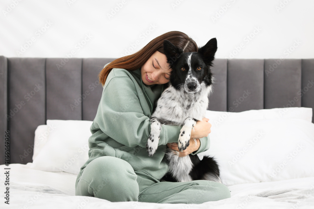 Fototapeta premium Woman with her cute Border Collie dog on bed at home