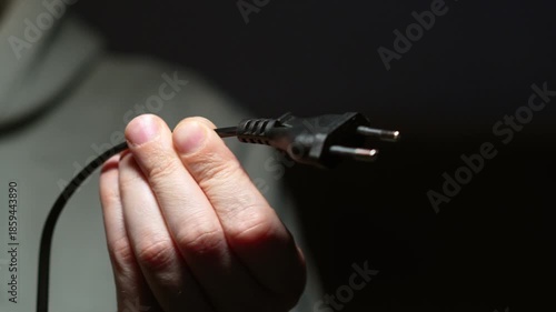 A person holding a black electrical plug and a long cable.
Connecting electrical appliances to a power outlet.
Household electrical appliances