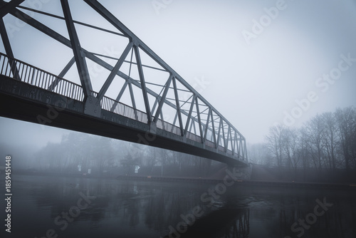 Metal bridge on the Mittellandkanal in Bramsche, Germany, in winter fog — moody canal landscape