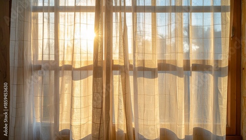 “Sheer white curtains billowing in front of sunlit window with warm glow on wooden floor and trees outside”