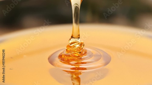 Honey Dripping from Spoon into Container.