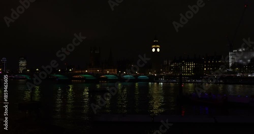 Red buses, traffic and people on Westminster Bridge over the River Thames at night, next to Big Ben and The Houses of Parliament, London, England
