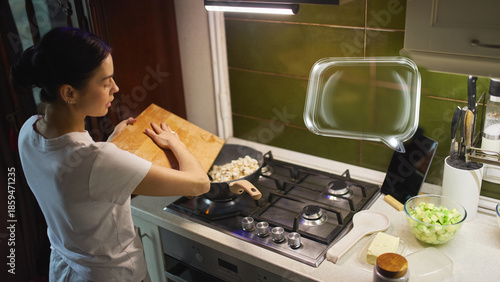 Photos Woman using tablet with AI cooking assistant while preparing vegetables in modern kitchen