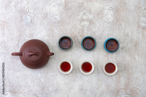 teapot and cups of black tea on a white wooden background
