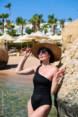 A wealthy businesswoman sunbathes beach of a luxury hotel.