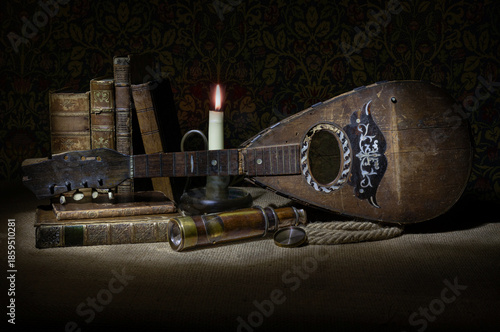 old broken, damaged mandolin with candle, candlelight, old leather books, rope, telescope, musical instrument