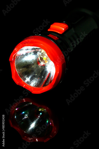 A flashlight on a black glass background