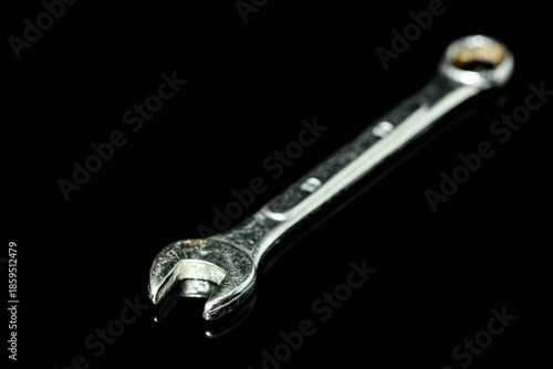 a close-up of a wrench on black glass