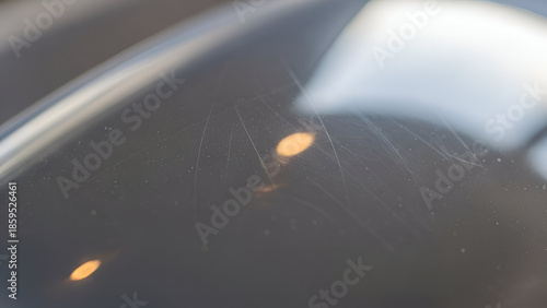 Fine scratches marring a dark glossy surface revealing the marks of everyday use and time with warm light reflections