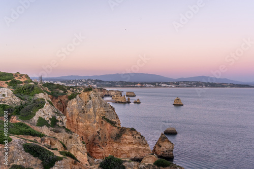 Cliffs and rocks near Praia do Camilo with mountains in the background during sunset in Algvare region of Portugal in Lagos