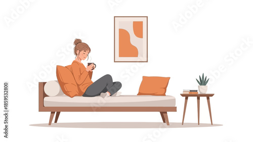 A young woman relaxes on a sofa, holding a cup and looking at her phone, in a minimalist living room.