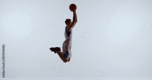 Basketball player midair holding ball above head in strong lift motion. Concept of vertical power, performance improvement, coaching materials, and dynamic sport storytelling.