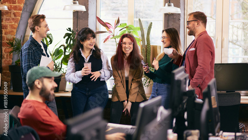 Informal office meeting with diverse team in modern workspace. Concept of inclusive modern office, cross functional collaboration, internal communication, team alignment.