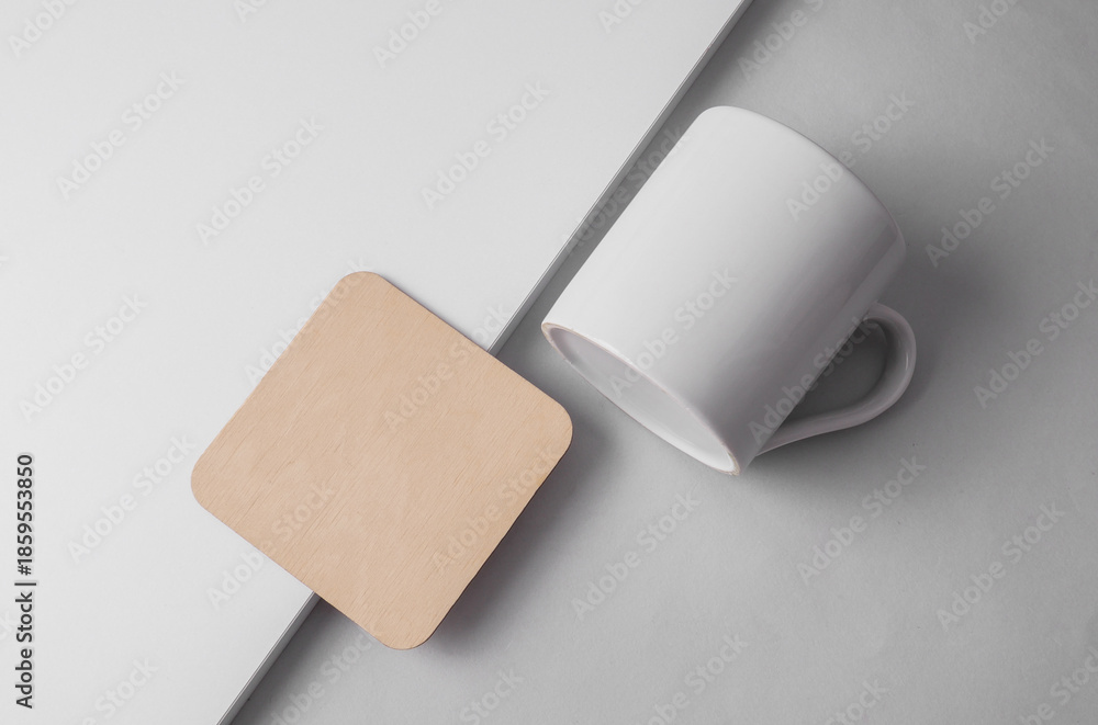 Obraz premium Wooden square coaster and ceramic cup on light background